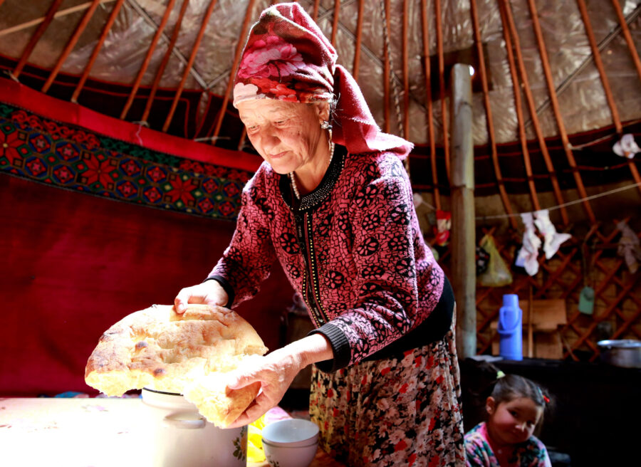 A Kyrgyz woman breaks bread at a nomad camp located about 250 kilometers south of Bishkek, 3000 meters above sea level on the high steppe plateau of the Suusamyr Valley, Kyrgyzstan, 10 August 2020. The valley is famous in Kyrgyzstan for kumis, a fermented dairy product traditionally made from mare's milk.